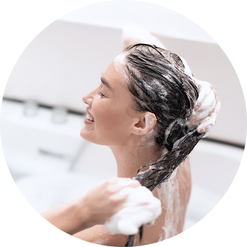Woman lathering shampoo into her scalp in the shower